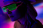 Woman wearing neon sunglasses in dark