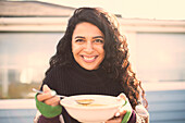 Happy woman eating chowder on sunny patio