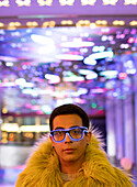 Young man in feather boa and neon glasses