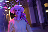Woman in fedora under neon lights