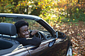 Happy woman driving convertible in autumn park