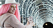 Woman with pink hair photographing arch lights