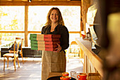 Happy female pizzeria owner holding pizza boxes