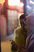 Young couple using smart phones on urban sidewalk