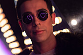 Young man with neon heart reflection in sunglasses