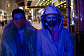 Couple wearing face masks on city sidewalk at night