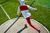 Female track and field athlete in hijab throwing discus