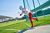 Female track and field athlete in hijab throwing discus