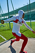 Female track and field athlete in hijab throwing discus