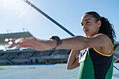 Focused female track and field athlete throwing javelin