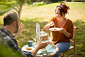 Happy couple enjoying cake and tea at sunny garden table