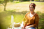 Happy woman enjoying cake at table in sunny summer garden