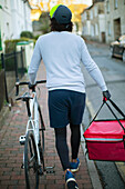 Male bike messenger delivering food in urban neighbourhood
