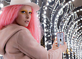 Woman with pink hair and smart phone photo of arch lights