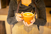Female barista holding cappuccino with heart foam