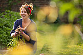 Happy woman harvesting fresh vegetables in backyard garden