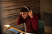 Happy young man with headphones working from home on laptop