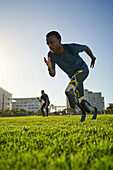Focused male amputee sprinter training in sunny sports field