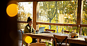 Businesswoman talking on phone on laptop in cafe