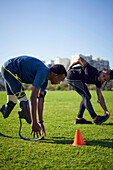 Coach and young male amputee athlete stretching in park