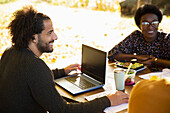 Happy businessman with laptop meeting with colleagues