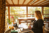 Thoughtful businesswoman working on laptop in restaurant