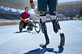 Male amputee and wheelchair athletes on sunny sports track