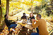Business people meeting and eating at table in autumn park