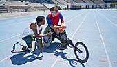 Male amputee and wheelchair athletes talking on track