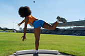 Female athlete throwing shot put in