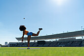 Female athlete throwing shot put in stadium