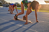Female athletes at starting blocks on sunny track