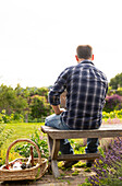 Man taking a break from gardening on bench in garden