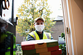 Delivery man in face mask delivering pizza at front door