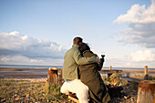 Couple hugging and drinking wine on sunny winter beach