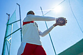 Female athlete throwing discus under sunny blue sky