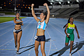 Female athlete celebrating victory on track at night