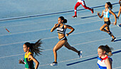 Female athletes running in competition on blue track