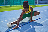 Female athlete with javelin stretching on sunny track
