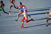 Female athletes running in competition on sunny track