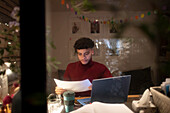 Focused young man working from home on laptop at night