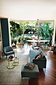 Open-plan interior with green walls, various seating and dining area in front of glass wall