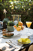Gedeckter Frühstückstisch mit Orangen und Croissant auf der Terrasse