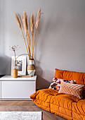 Orange two-seater sofa next to low sideboard