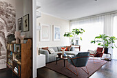 Graue Sofagarnitur, Zimmerpflanzen und Sessel mit Metallstruktur im Wohnzimmer mit dunklem Boden
