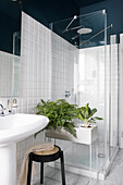 Shower cubicle in the bathroom with white wall tiles below blue walls and ceiling