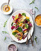 Salad made of spinach, orange, grilled halloumi, red onion and endive