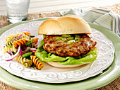 A Turkey Burger with lettuce and a side dish of pasta salad