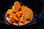 Semolina pudding with mango, biscuits and gold leaf