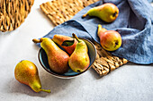Organic ripe pears in ceramic bowl on rustic table